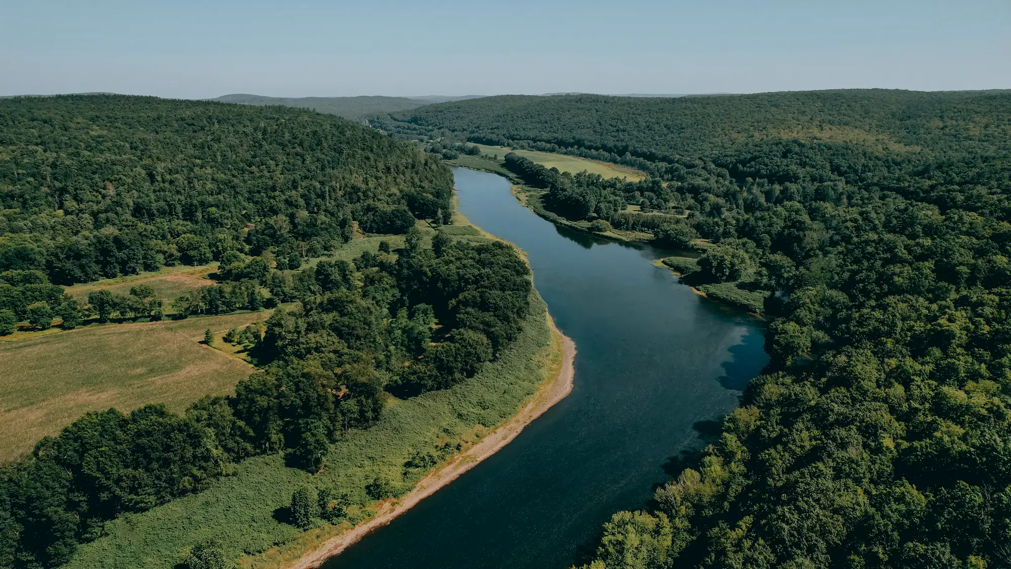 Aerial view of the Delaware River winding between forested hills in New York